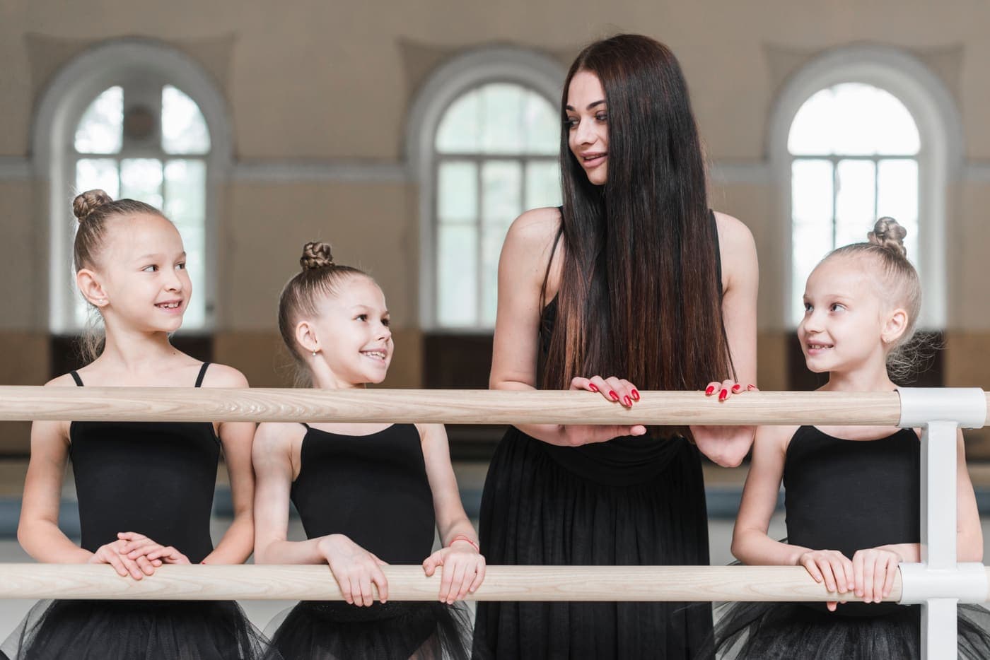 Profesora de danza con alumnas en la barra del estudio